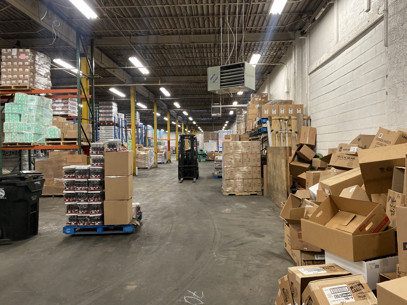 Forklift operating between rows of stocked inventory